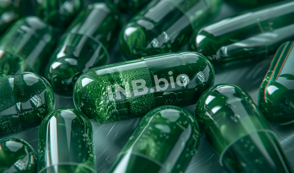 Close-up of green capsules scattered on a surface, with “NB.bio” printed on one of the capsules.