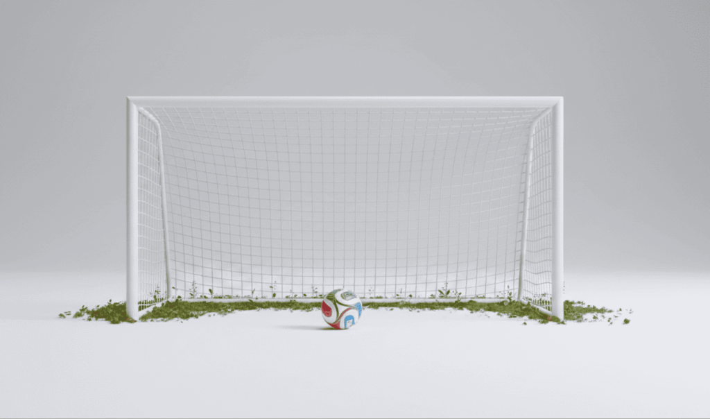 A white soccer goal with netting and small green plants growing at the base, and a colorful soccer ball placed in front on a smooth white surface.