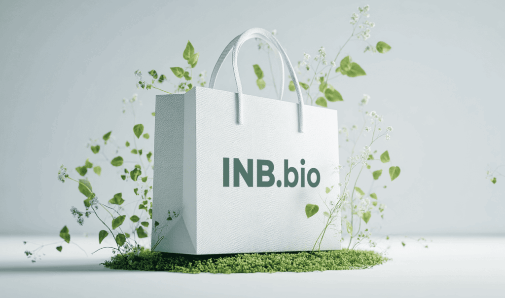 White textured shopping bag with "INB.bio" text, surrounded by green leaves and small white flowers on a light background.